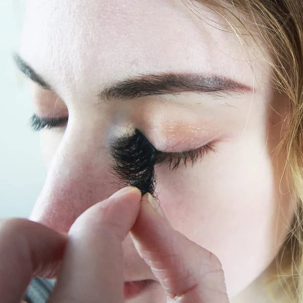 Girl with blode hair trying to remove eyelash extension on her eyes